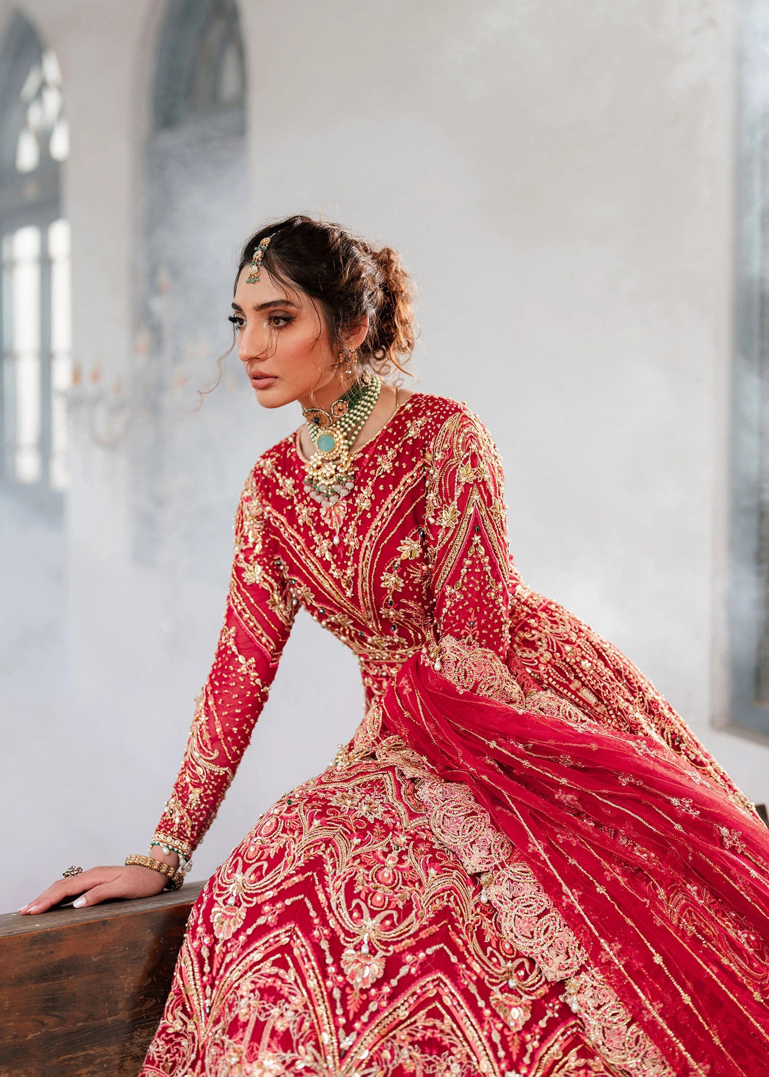 Buraqstore bride posing in pakistani full red bridal dress with intricate net embroidery and dupatta styling