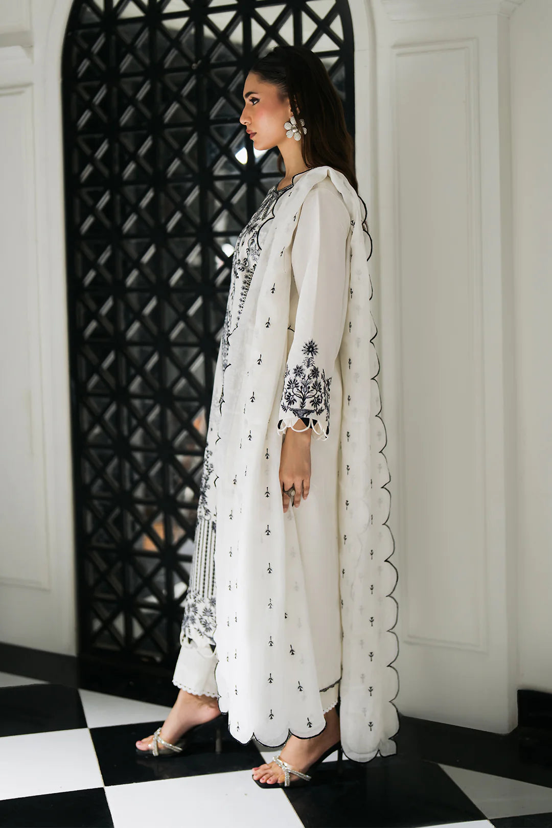 Woman posing in a white lawn 3 piece set with black embroidery from the Sidra Fahad collection, featured at Buraq Store