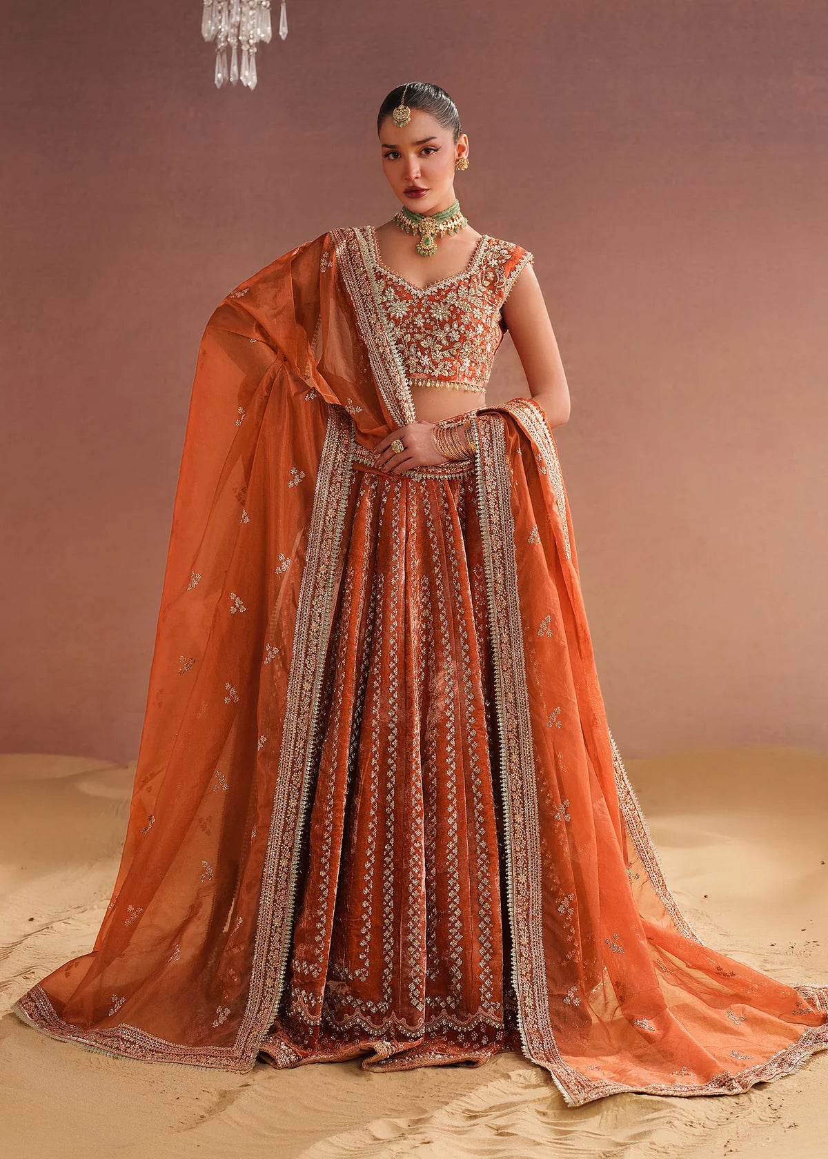 Bride wearing orange bridal lehenga in velvet embroidery by Buraqstore