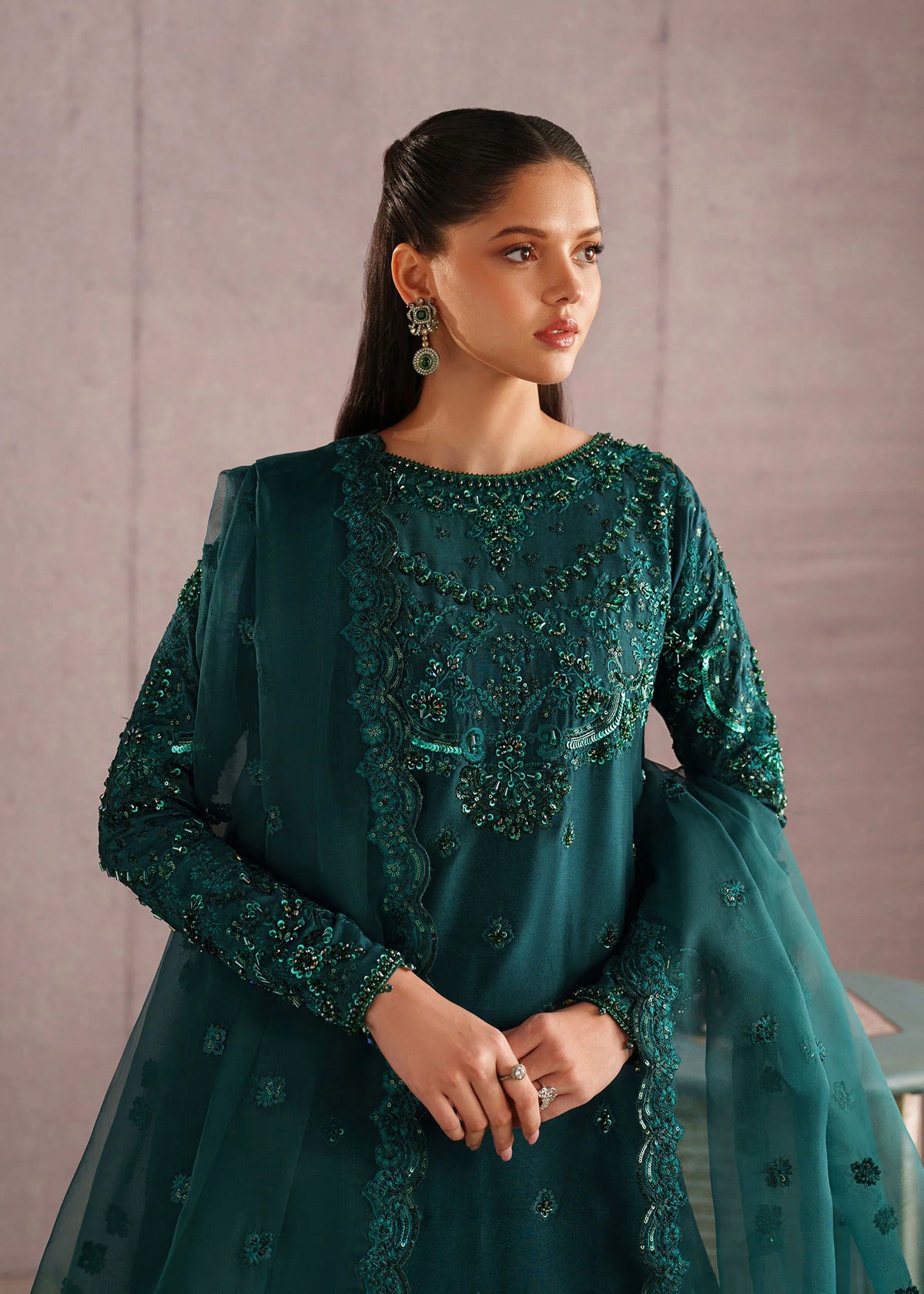 Woman posing in a stylish deep emerald green Rameen embroidered tissue silk 3 piece outfit from the Dastoor collection sale, featured at Buraq Store