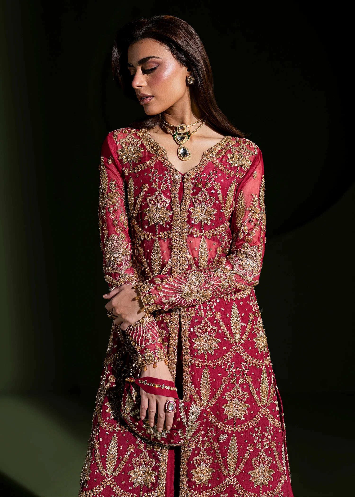 Buraqstore bride posing in deep red bridal dress with full embellishment and dupatta drape