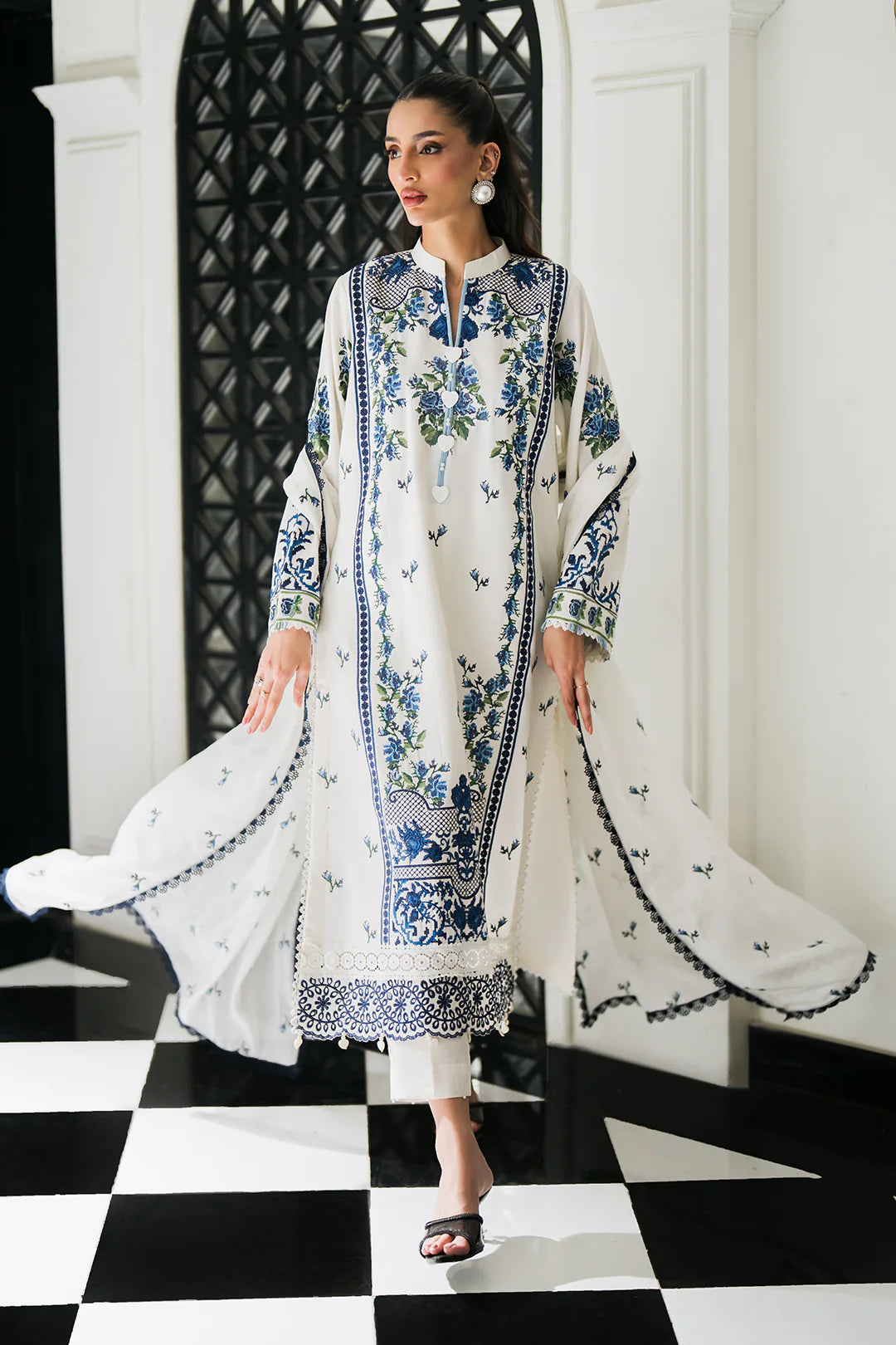 Woman posing in a white embroidered 3 piece suit from Sidra Fahad official website, featured at Buraq Store