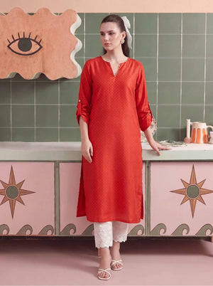 Model wearing coral color dress, a stitched solid dyed cambric 2-piece set with shirt and trouser, front view from Buraqstore