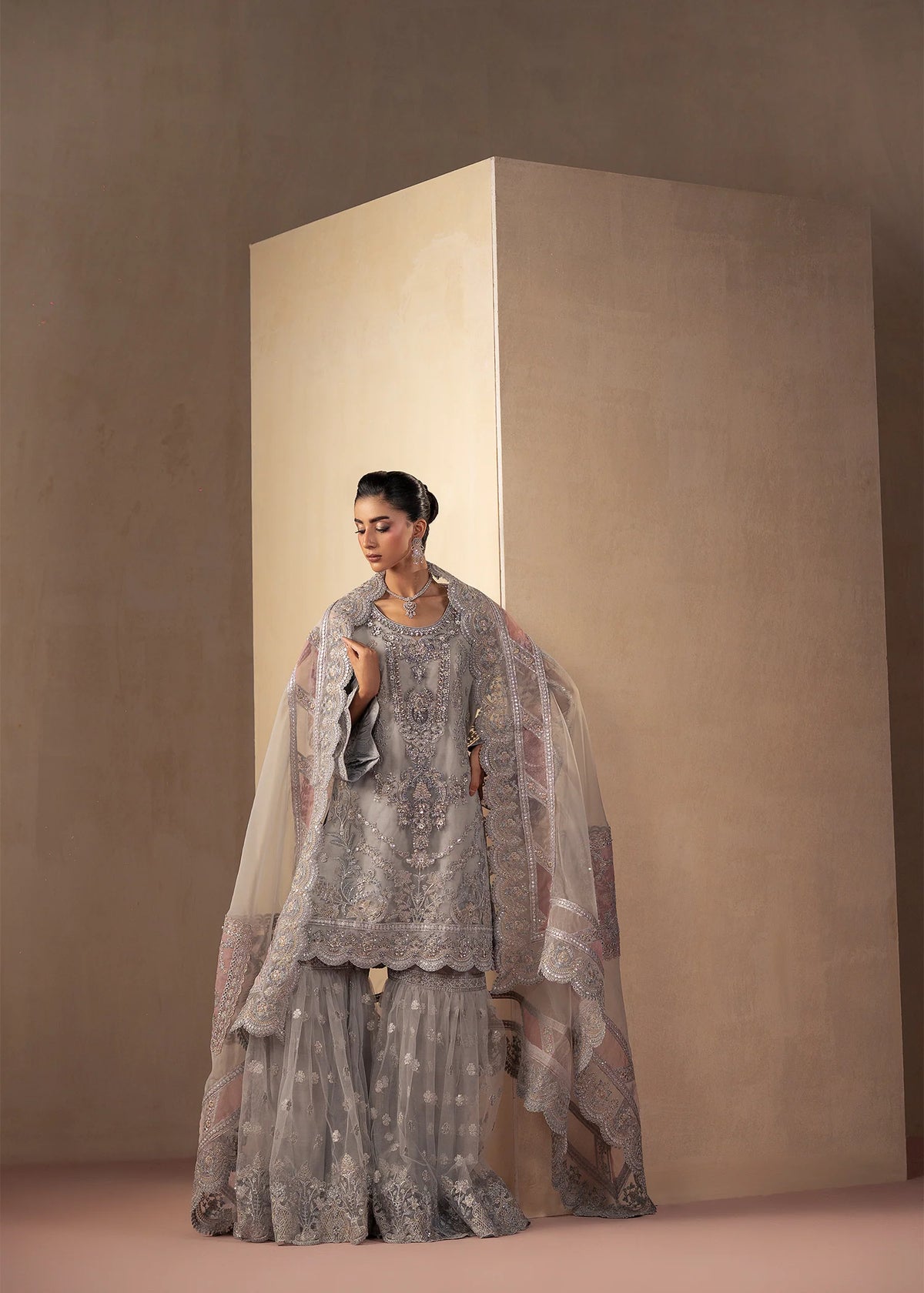 Model wearing silver colour dress as a festive outfit, shop the embroidered gharara 3-piece set at Buraqstore